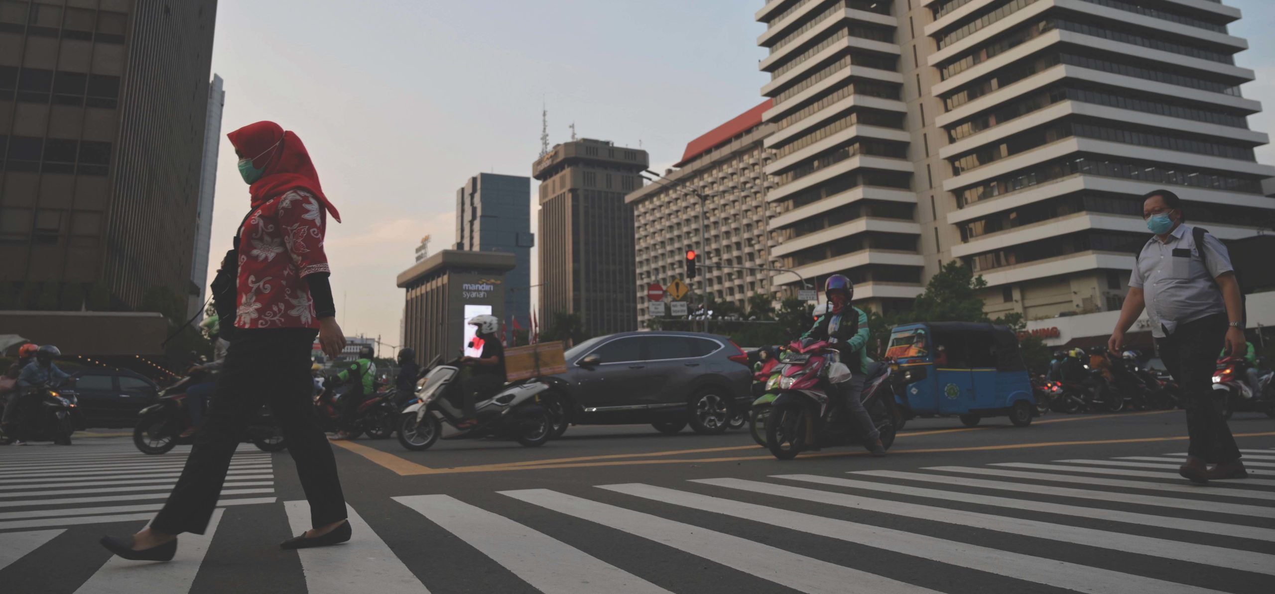 a busy street full of cars, motorcycles, and people