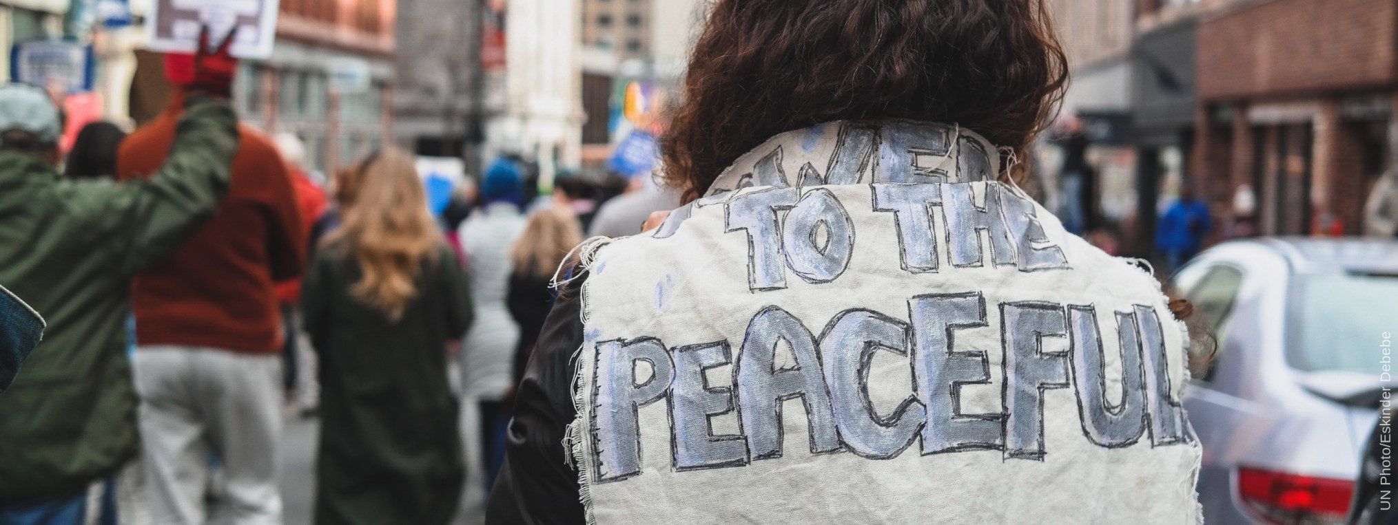 a crowd of people with focus on a person wearing a jacket saying power to the people