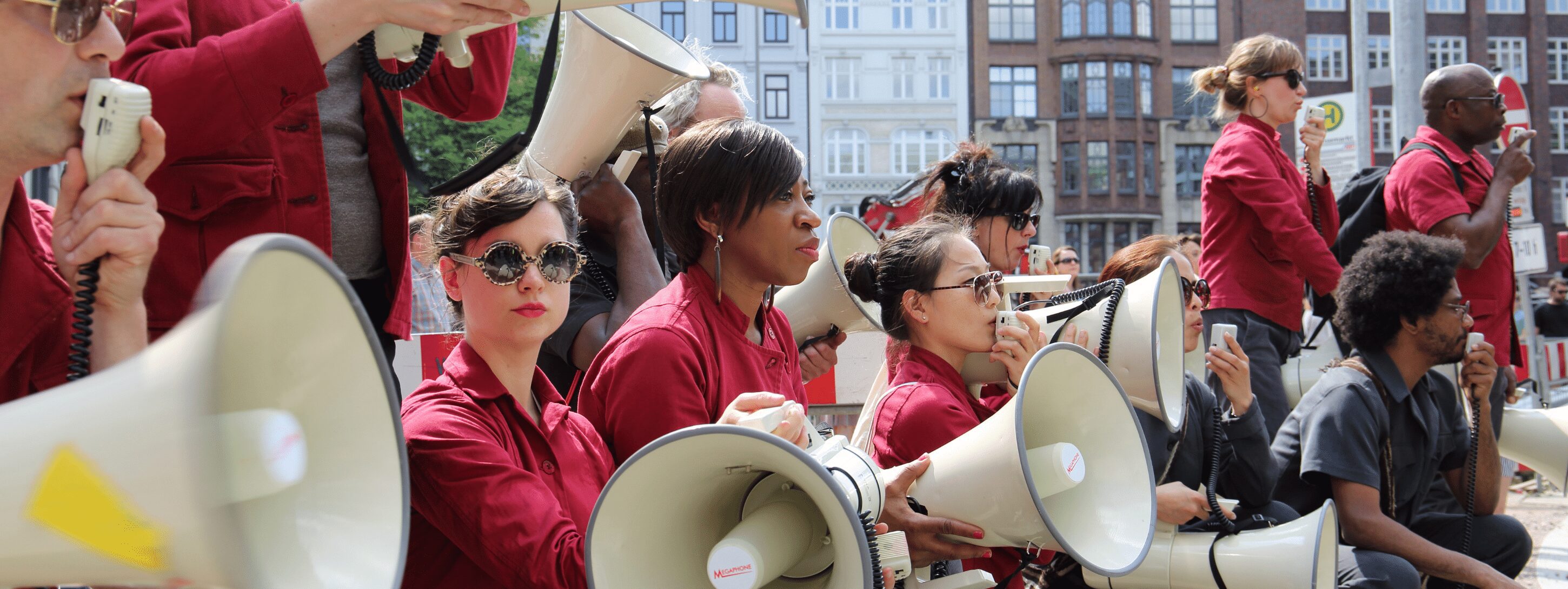 Women in red shirts stand with loudspeakers