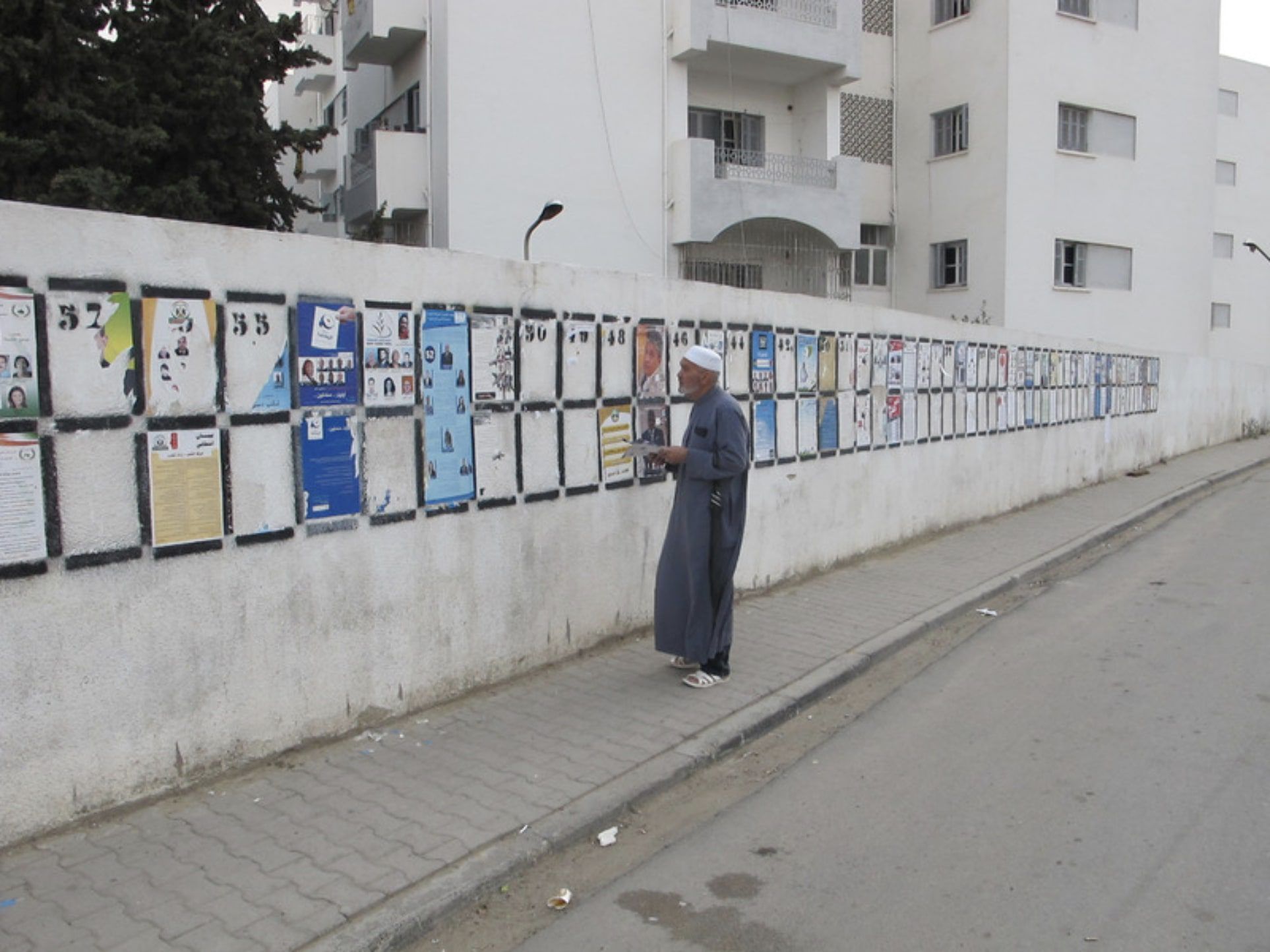 Middle Eastern man reads posters on a wall