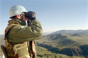 UN officer looking over mountains with binoculars