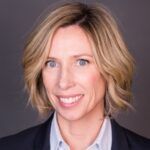 Headshot of Renata Dwan. Person with short blonde-brunette hair wearing a collared shirt and blazer.
