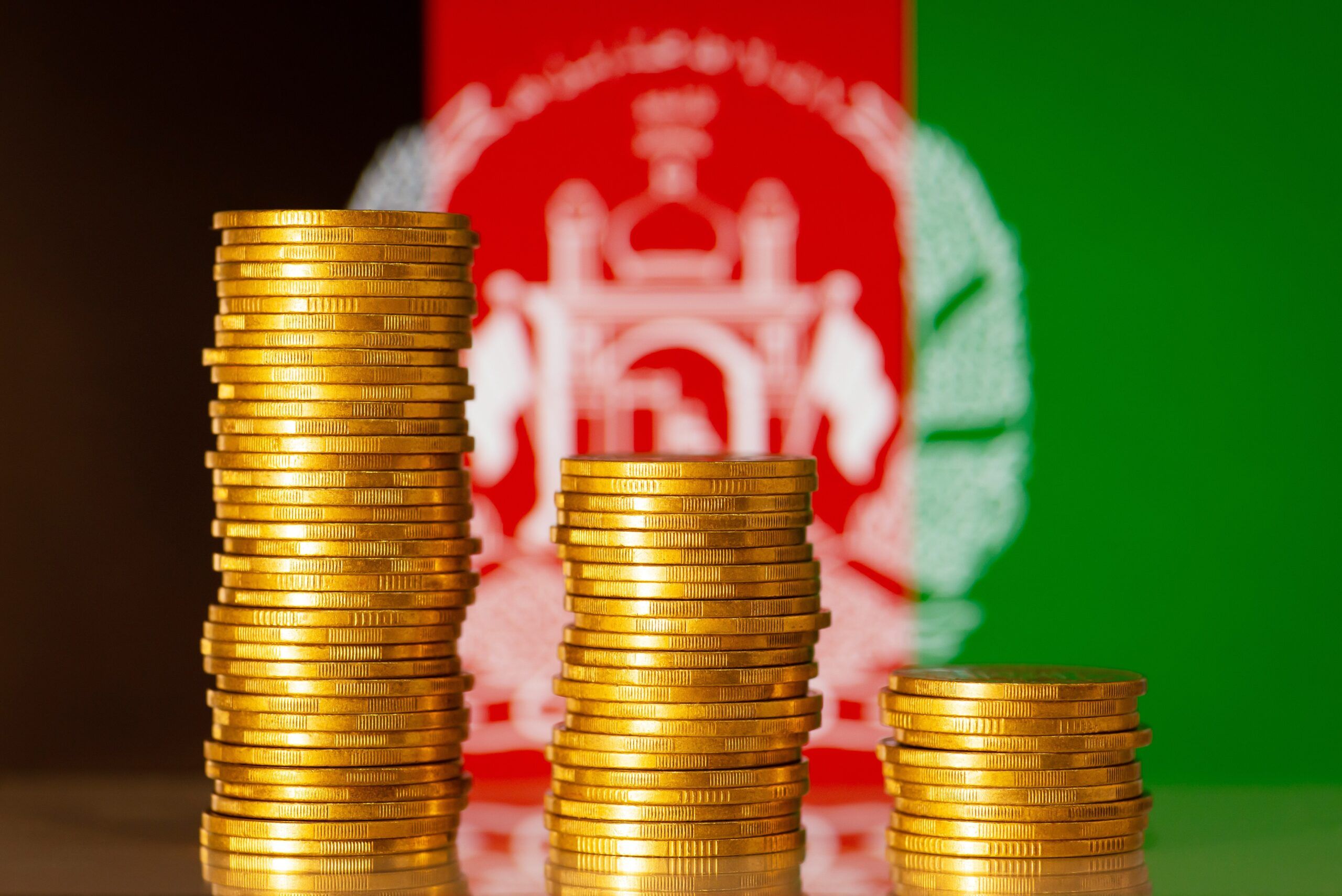 Stacks of gold coins in front of Afghanistan flag