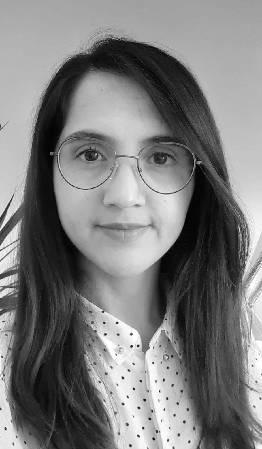 Medium shot of Guler Gulsen, a young woman with long black hair, wearing glasses and a white shirt with polka dots