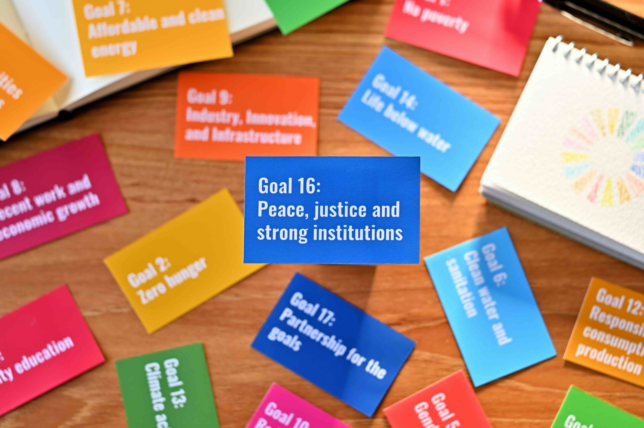 Card with the statement Goal 16:Peace, justice and strong institutions on table one of the goals of the SDGs and a symbol.