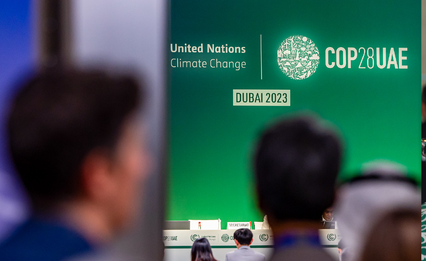 Bokeh photo of mainstage (with green background) at COP28 in the United Arab Emirates.