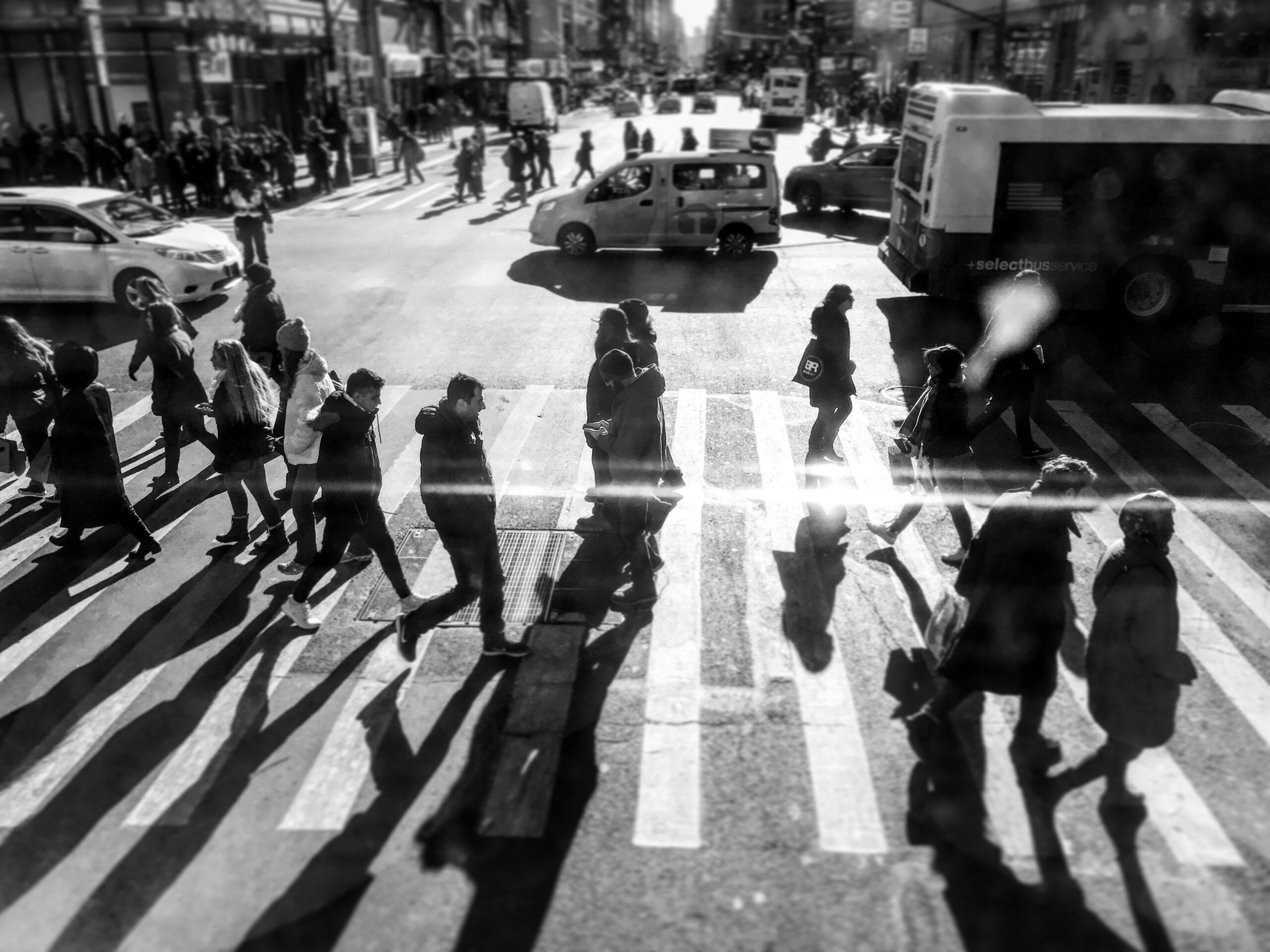 Black and white photo of people walking across a NYC crosswalk