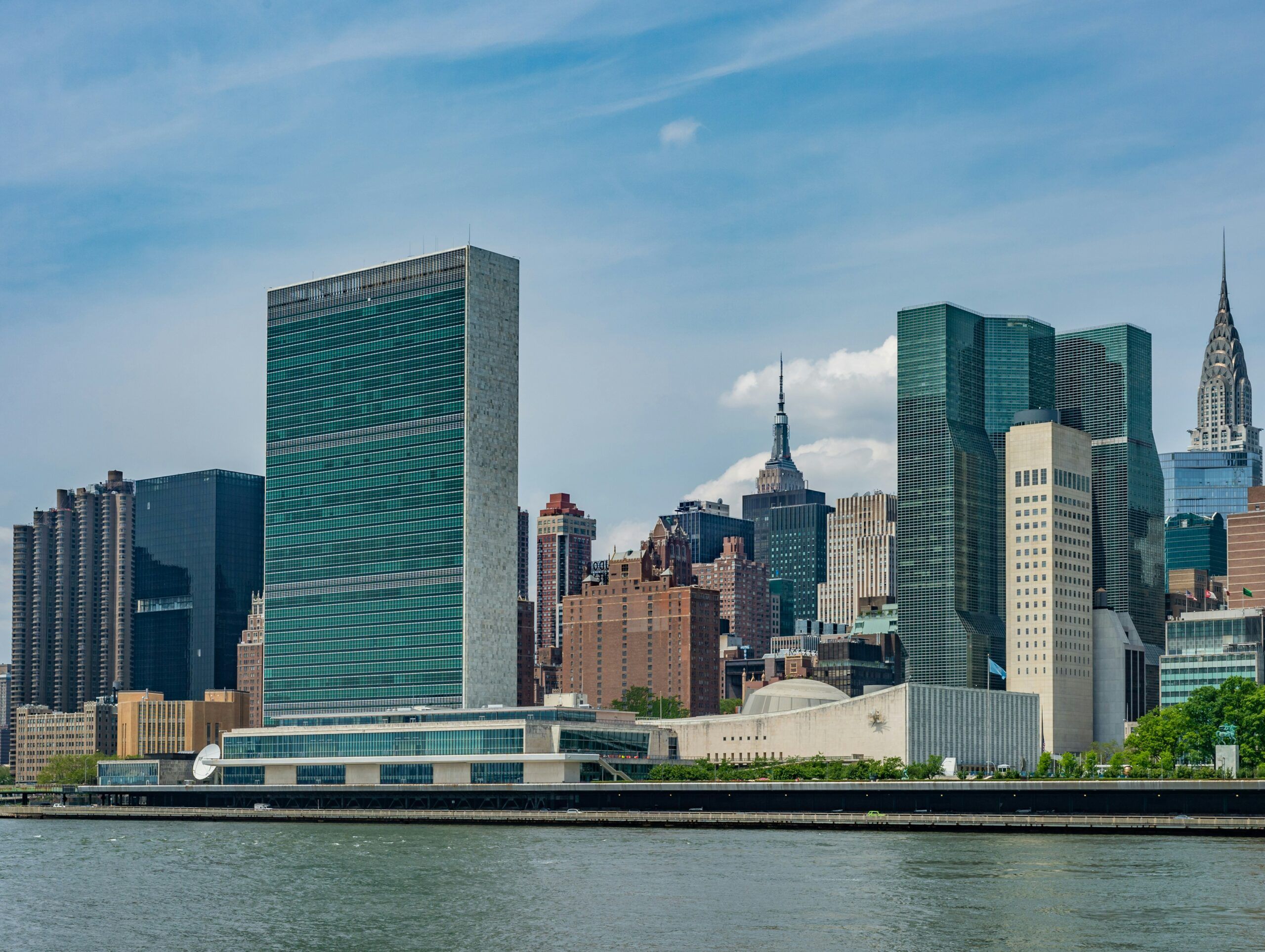 A view of the Manhattan skyline from Roosevelt Island, with the United Nations building in the foreground and the Empire State and Chrysler buildings visible.