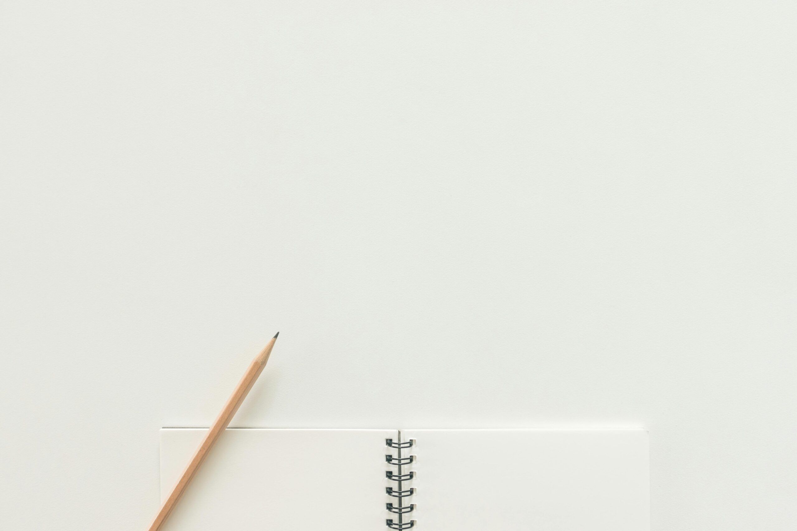 Open notebook with a pencil on top on a white background.