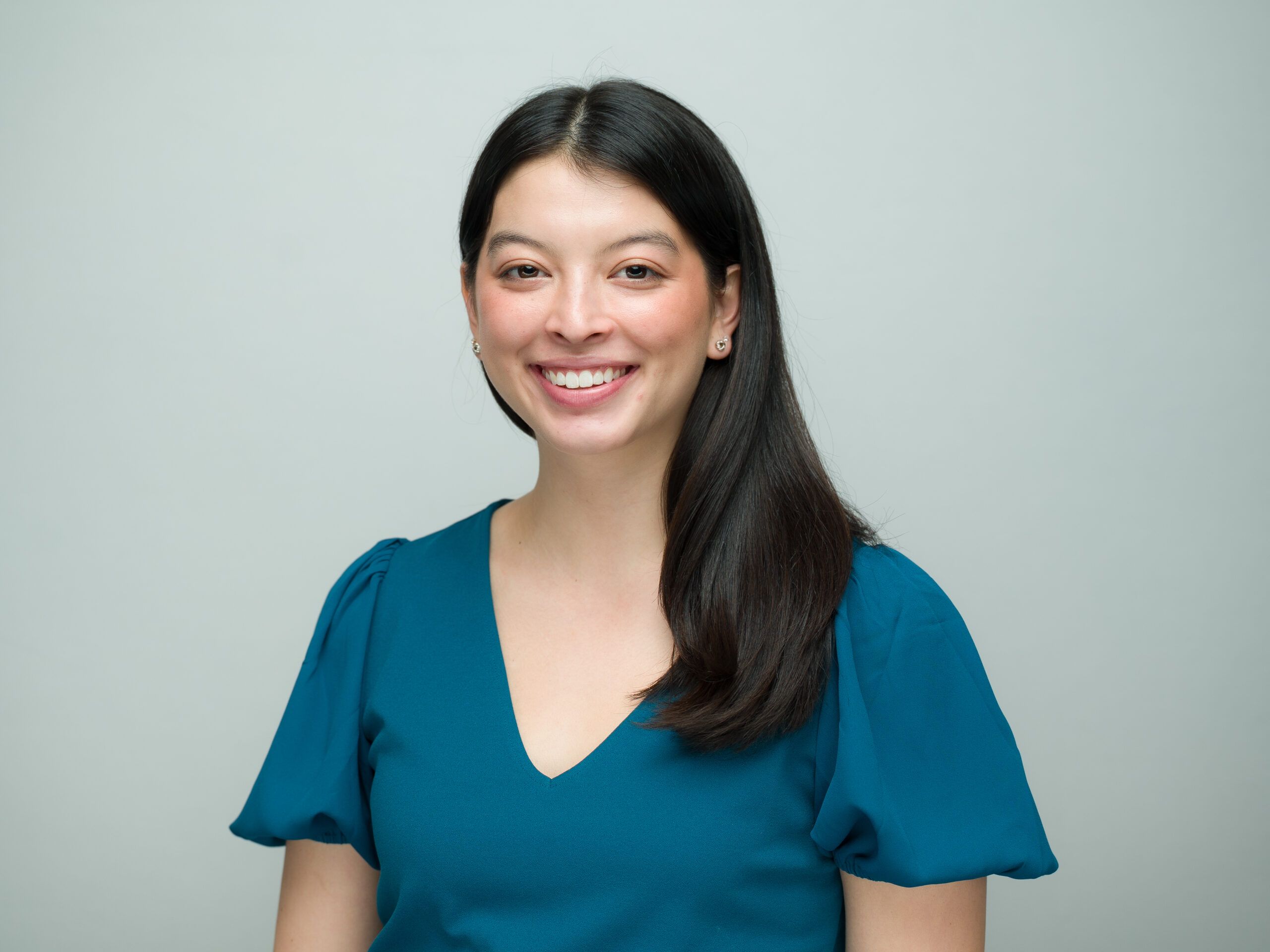 Headshot of a person with long brown hair and a teal top.
