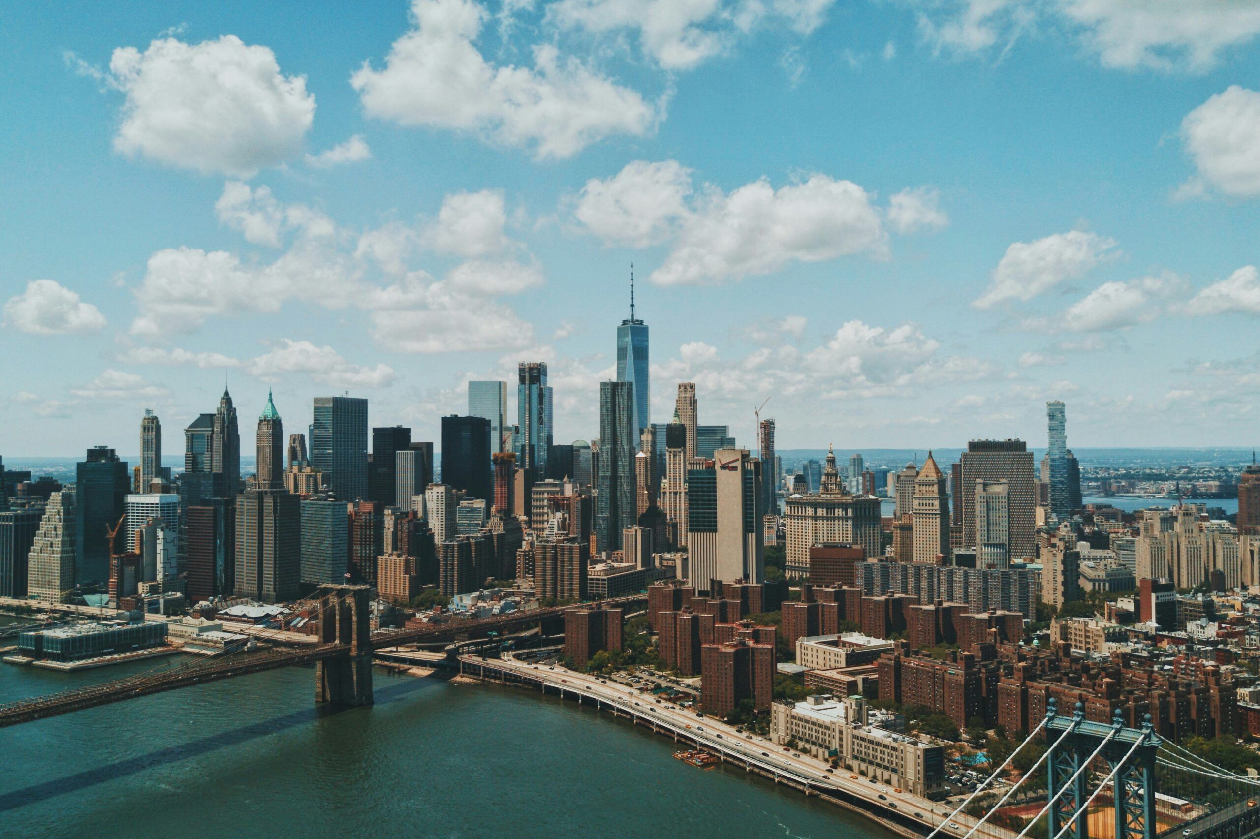 New York City skyscrapers/skyline against a cloudy blue sky.