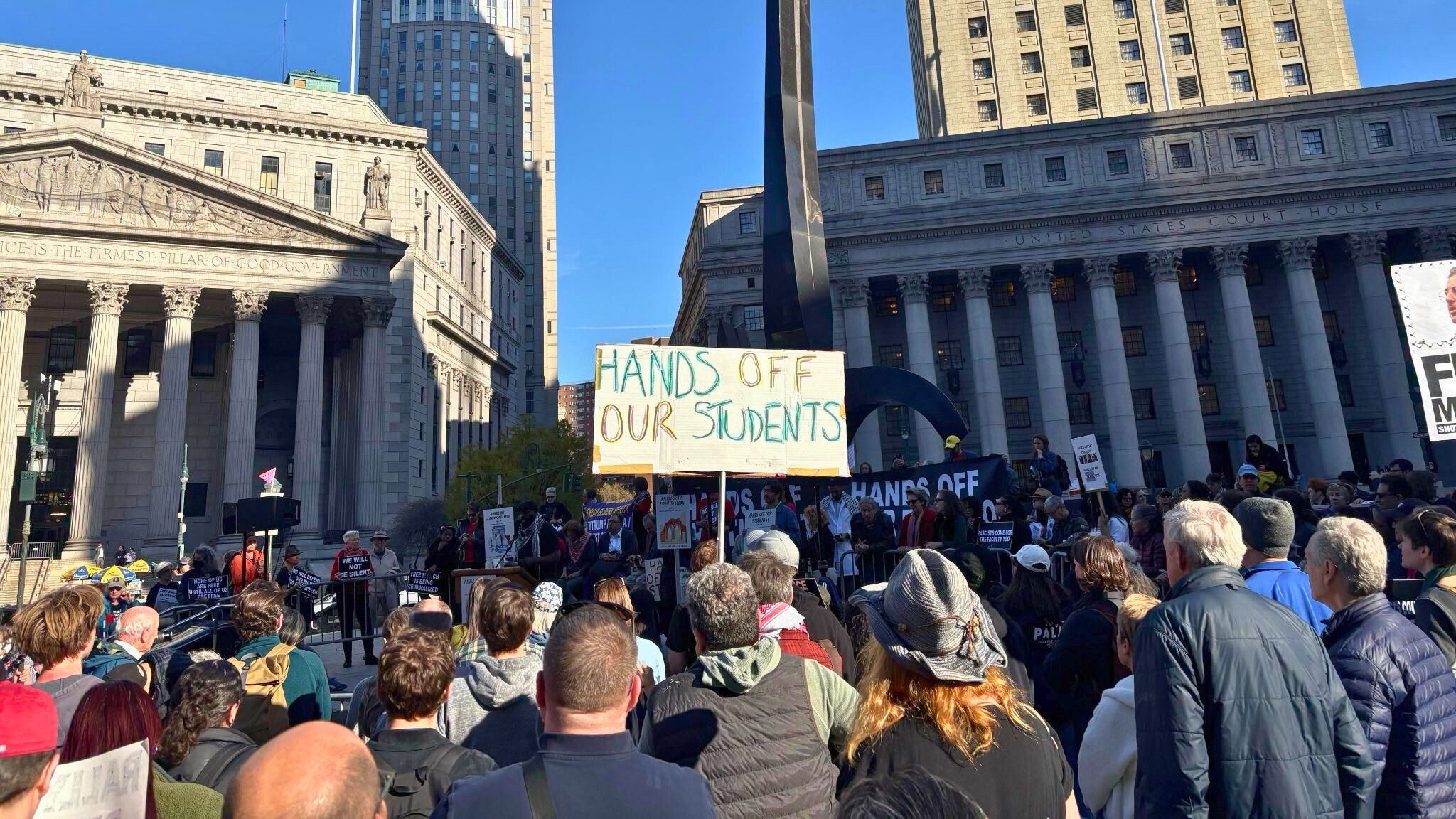 Protesters in a square holding signs.