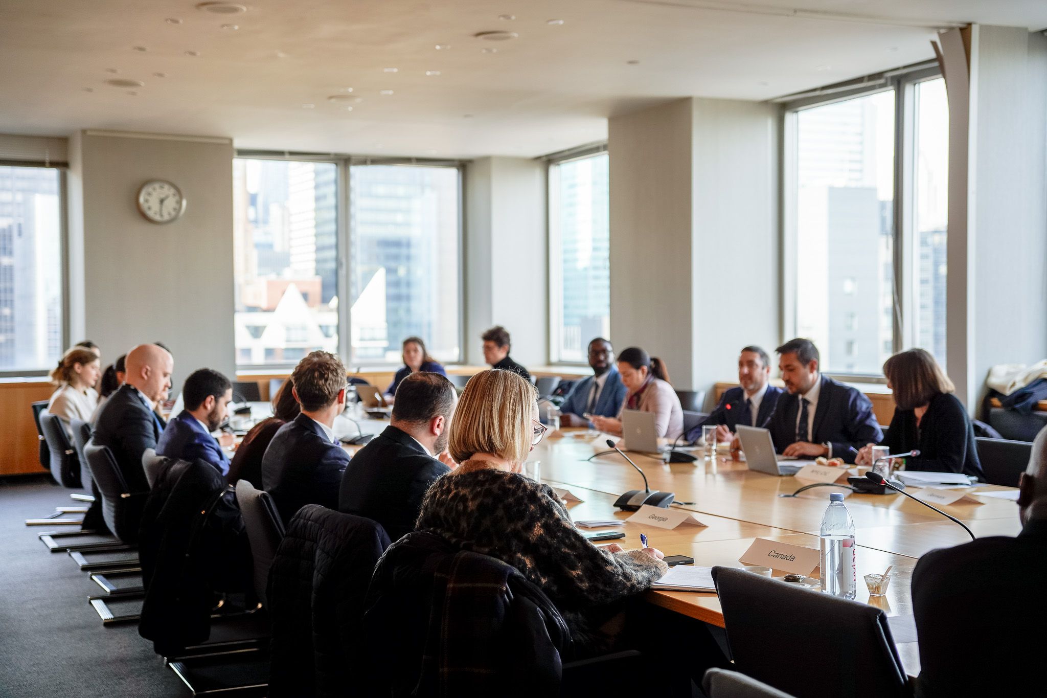 Group of people at a meeting seated around a rectangular table.