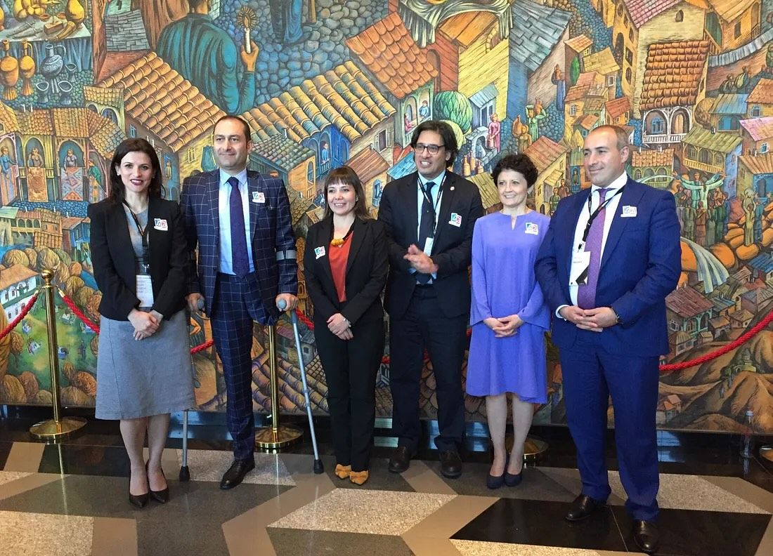Group of ministers of justices taking a photo in front of a colorful artwork wall.