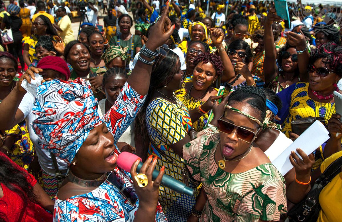 African woman sepaking into microphone in large crowd