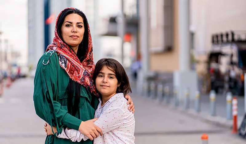 middle eastern woman with her arm around her daughter