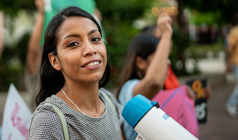 ethnic woman holding loudspeaker smiling at camera