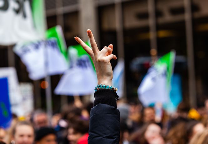 hand holding up peace sign in a protest crowd