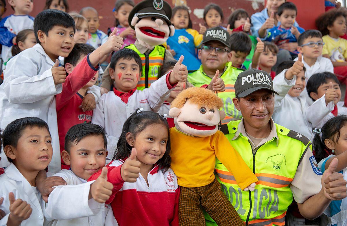 Ecuadorian children holding thumbs up with puppets and police officers