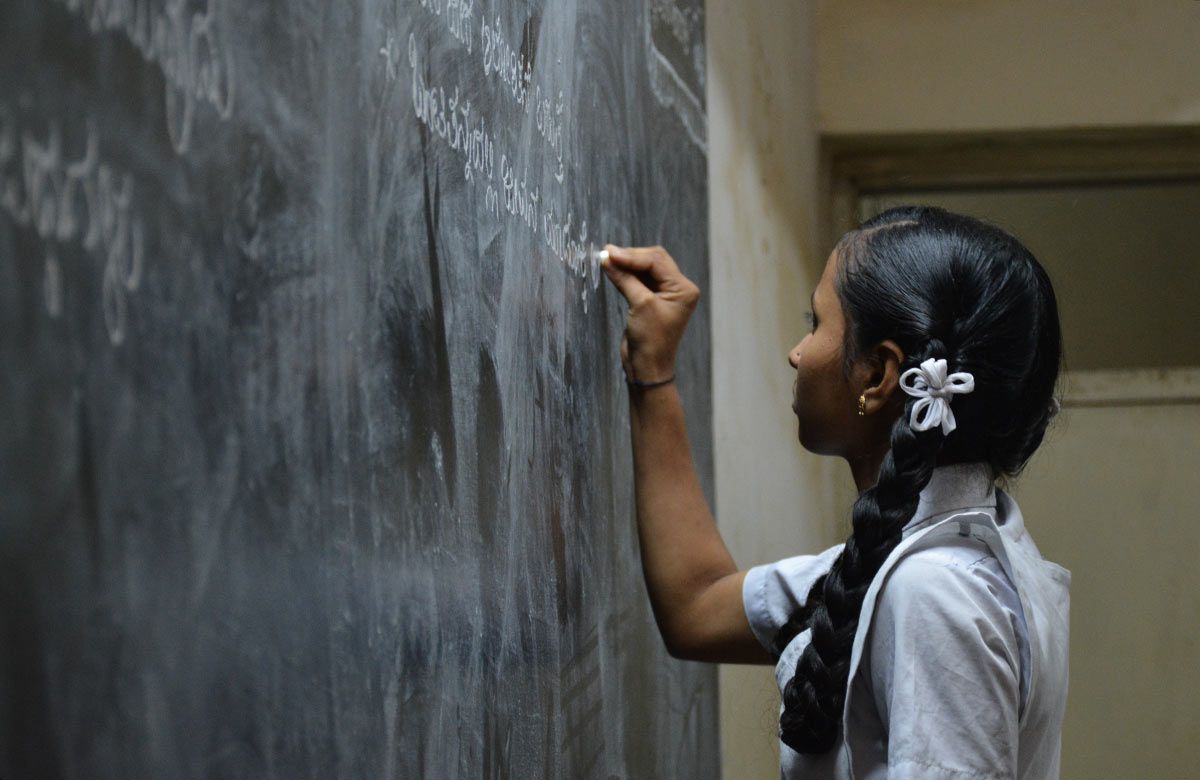 indian schoolgirl writes on chalkboard
