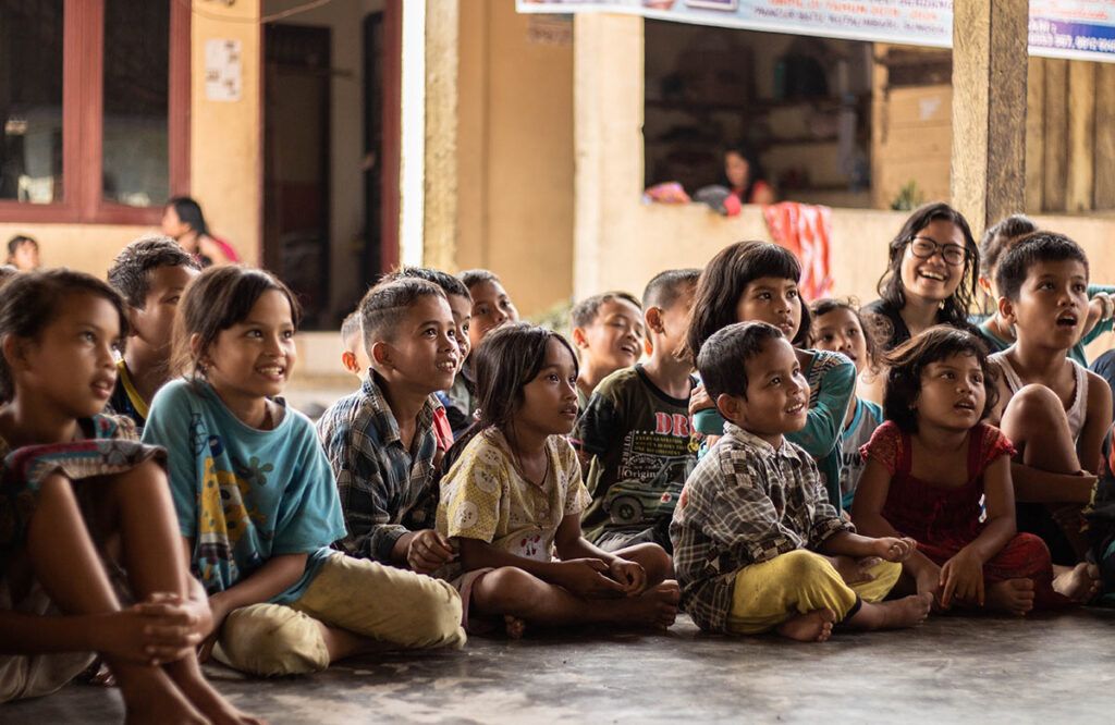 group of young foreign children sitting and listening