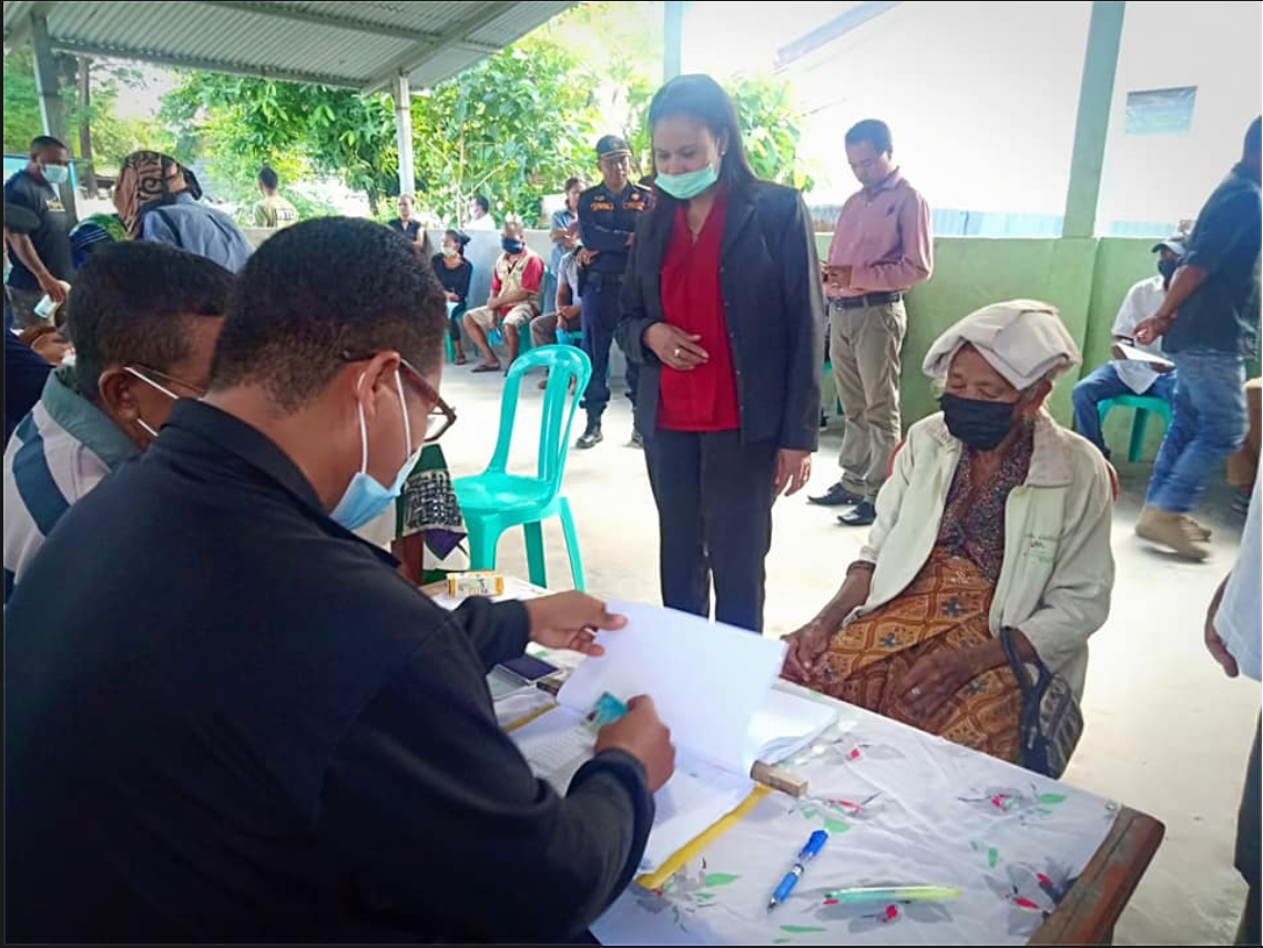 People in masks lining in front of a table to learn about COVID-19 cash transfer program in Timor-Leste