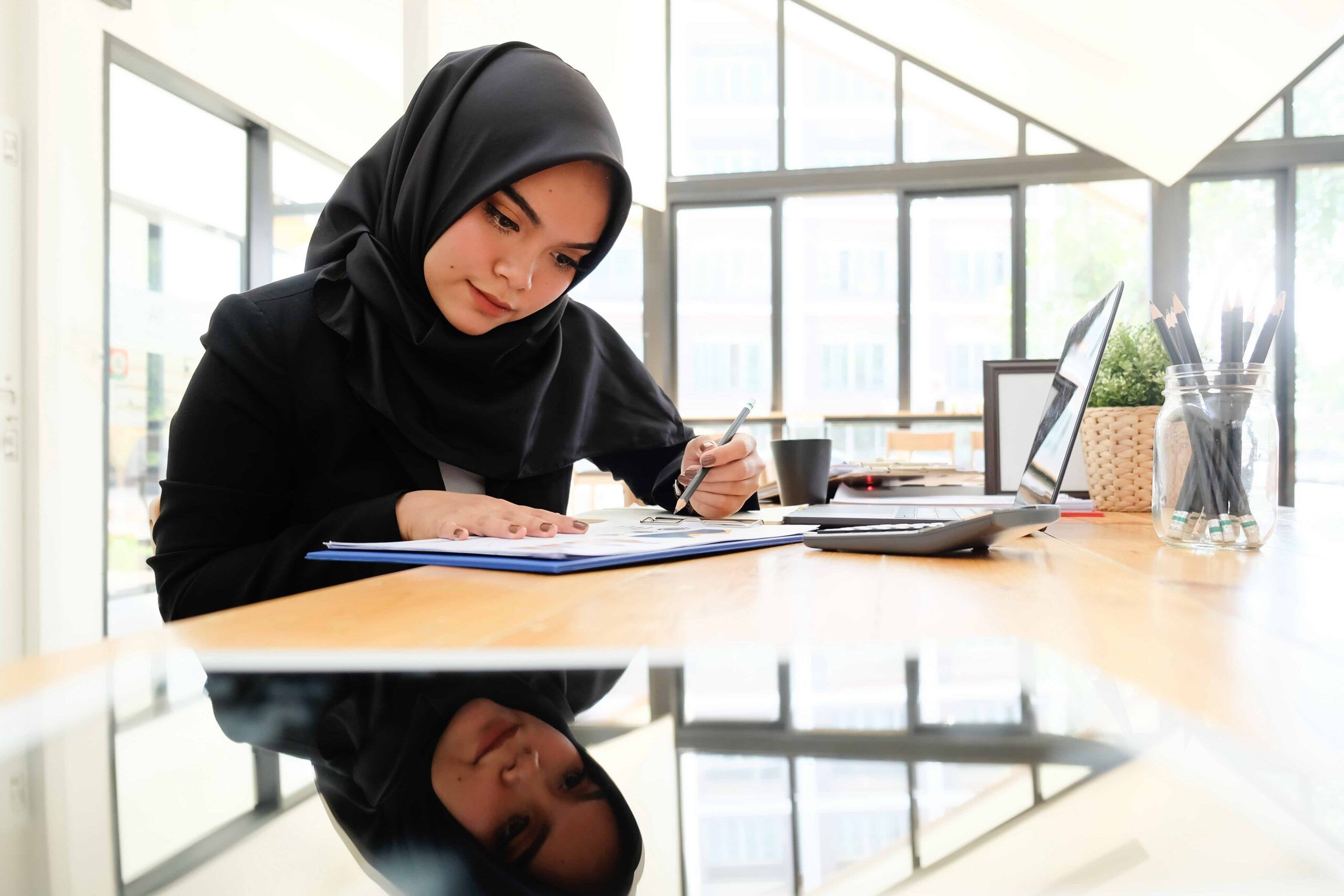 Islam Businesswoman working with document paper of finance on wood desk.