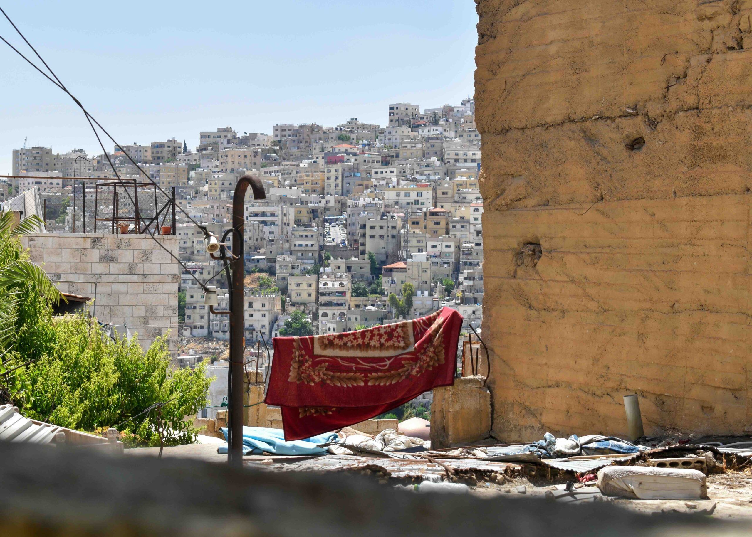 View of Amman Hillside with red blanket hanging off the clothesline between a pole and a wall.