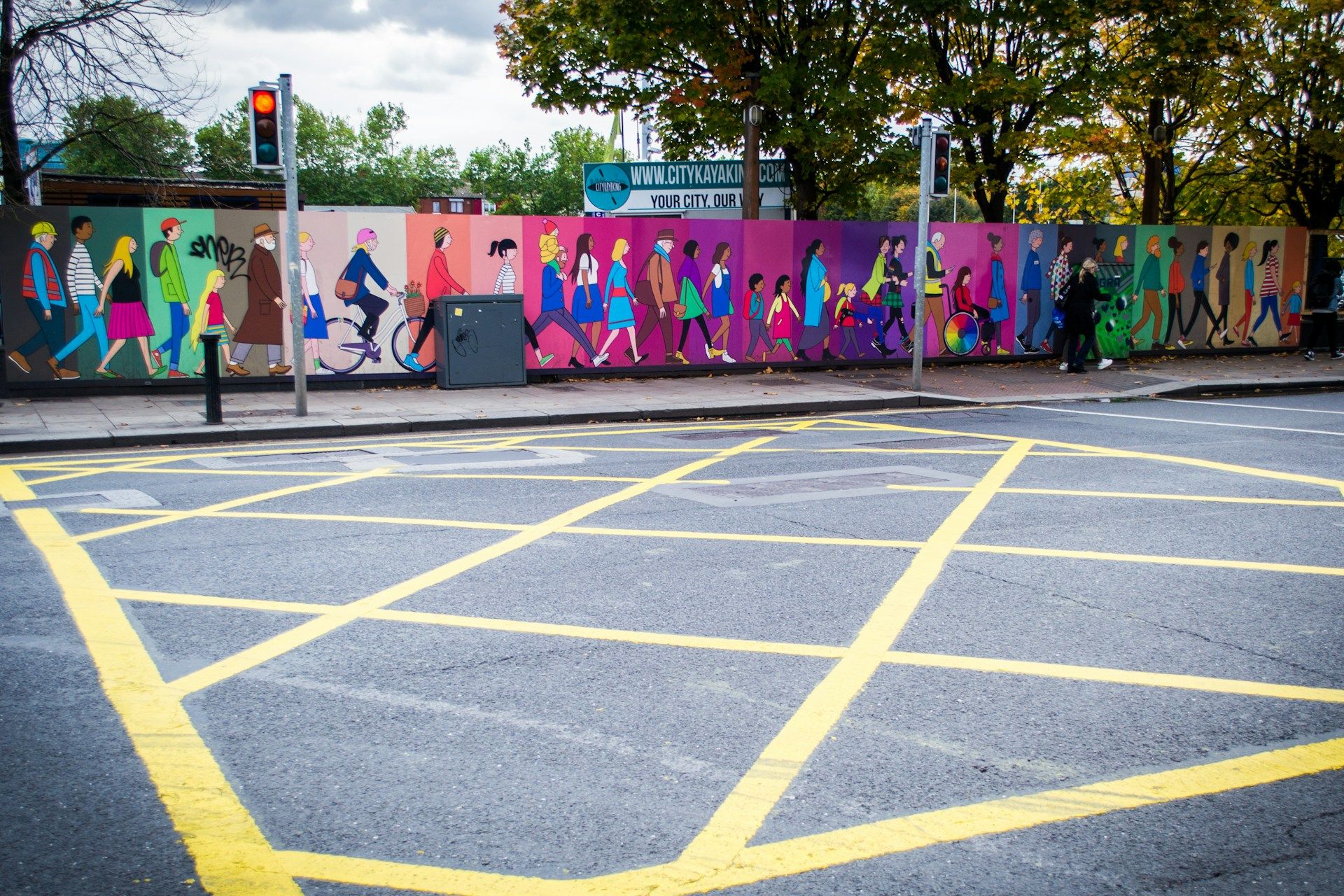 Colorful mural with person walking in front of it across a pedestrian walkway.