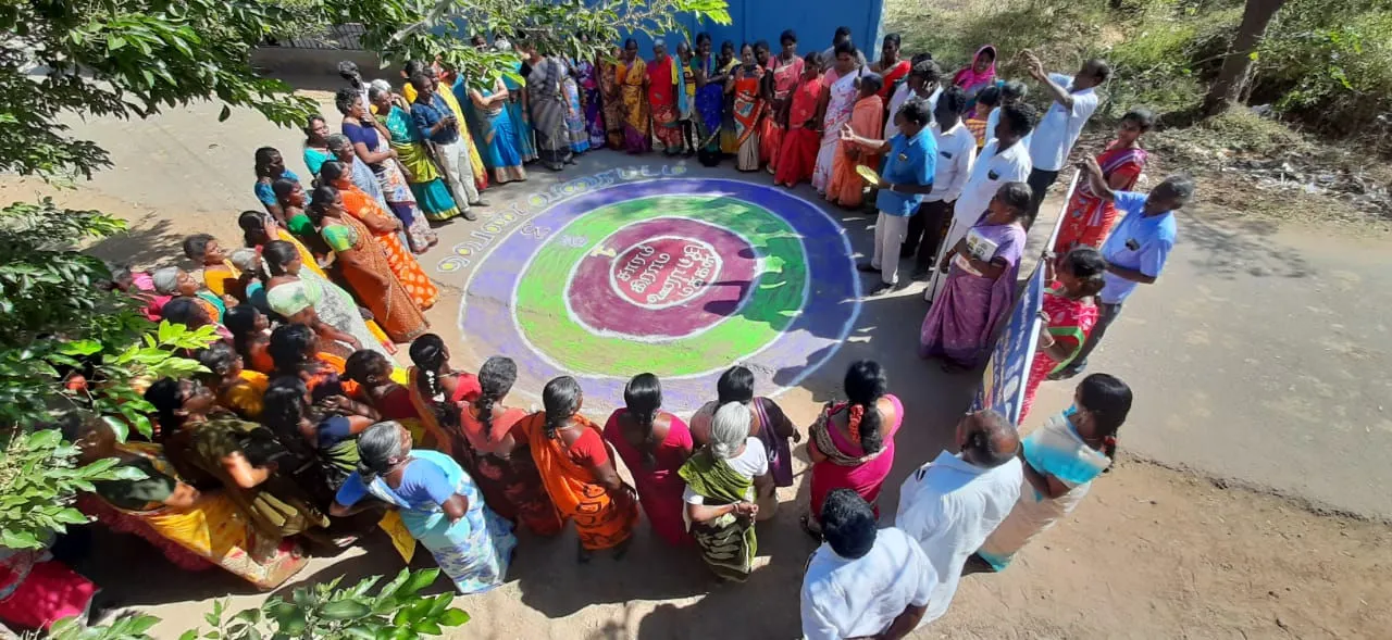 Photo of people gathered around a circle drawn on the ground.