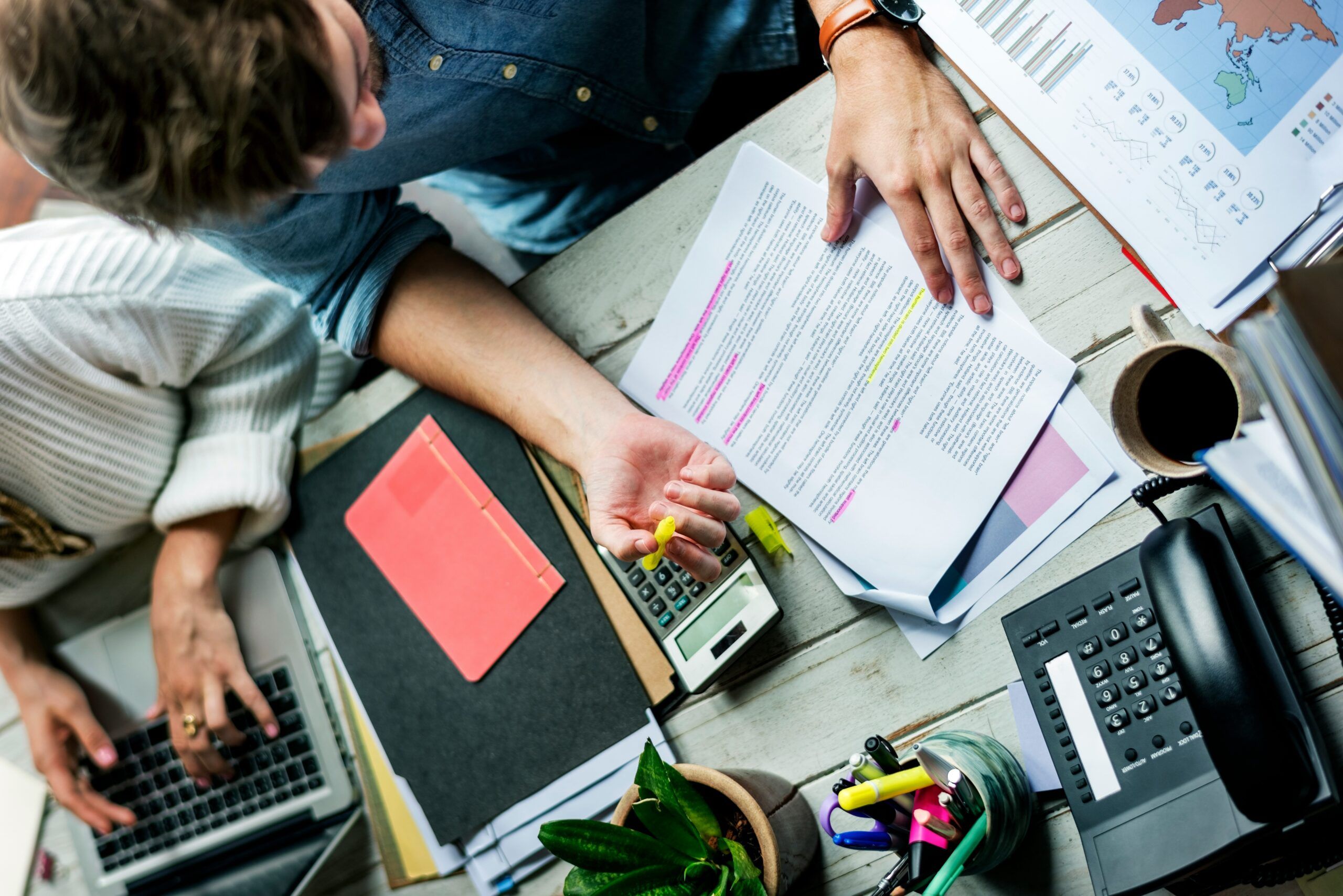 Overhead view of man proofreading paper on a desk.