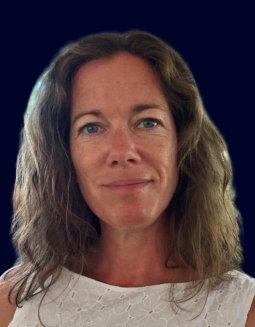 Headshot of a person with wavy brown hair wearing a white top.