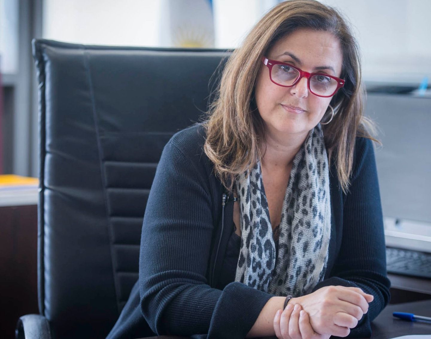 Headshot of a person wearing red glasses and a blue sweater + scarf