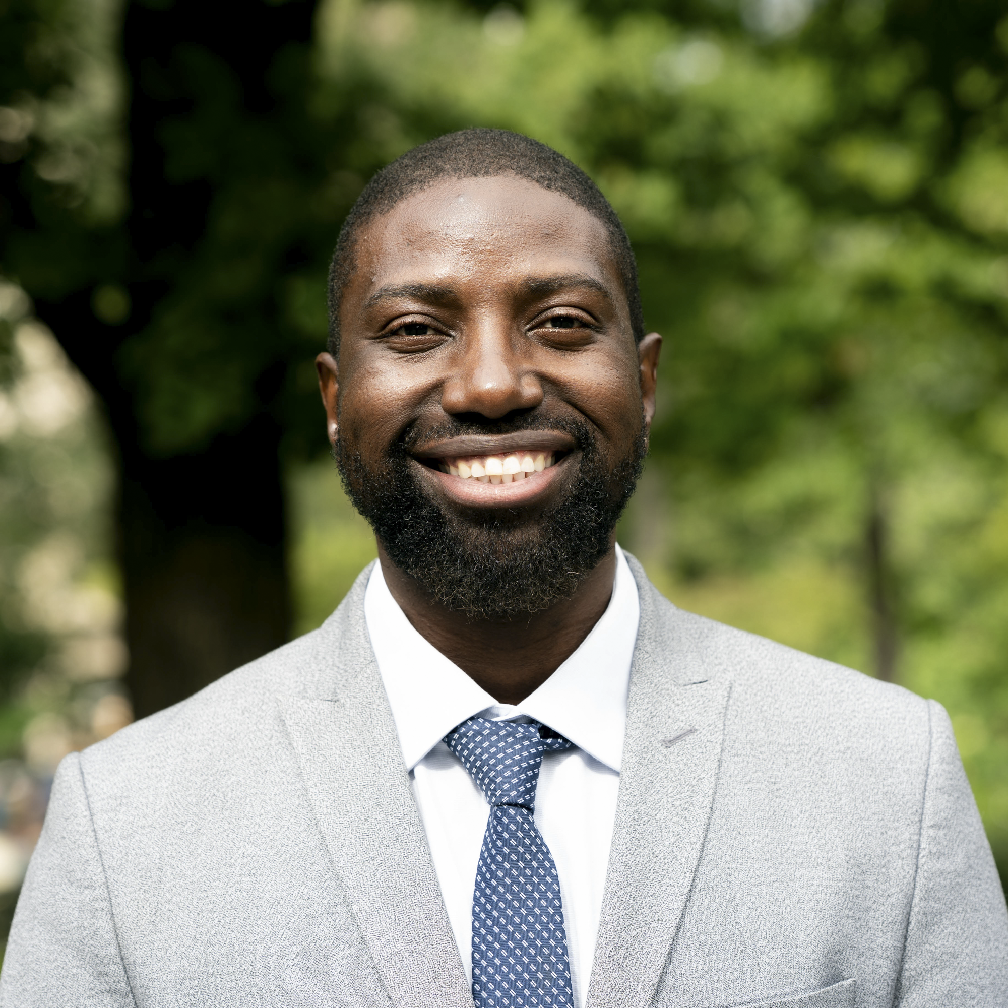 Headshot of person wearing a gray suit and blue tie.